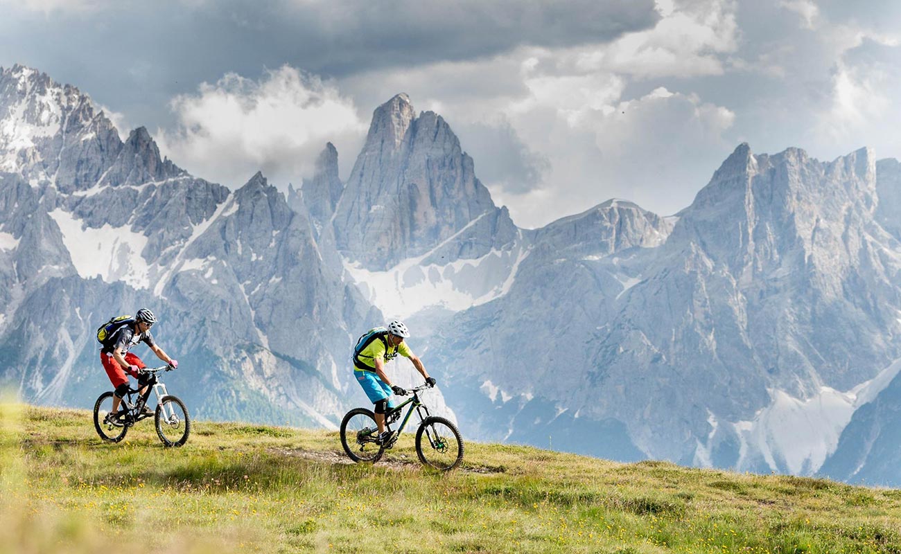 Two cyclists on a plateau and mountains of rock in the background