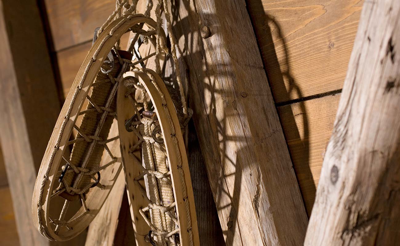 Old wooden snowshoes hung from a nail on a wall