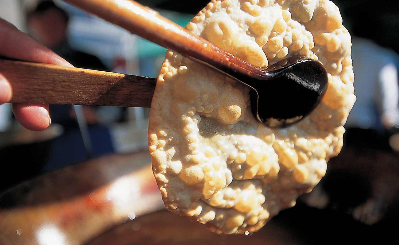 Una persona cucina dei krapfen dell'Alto Adige