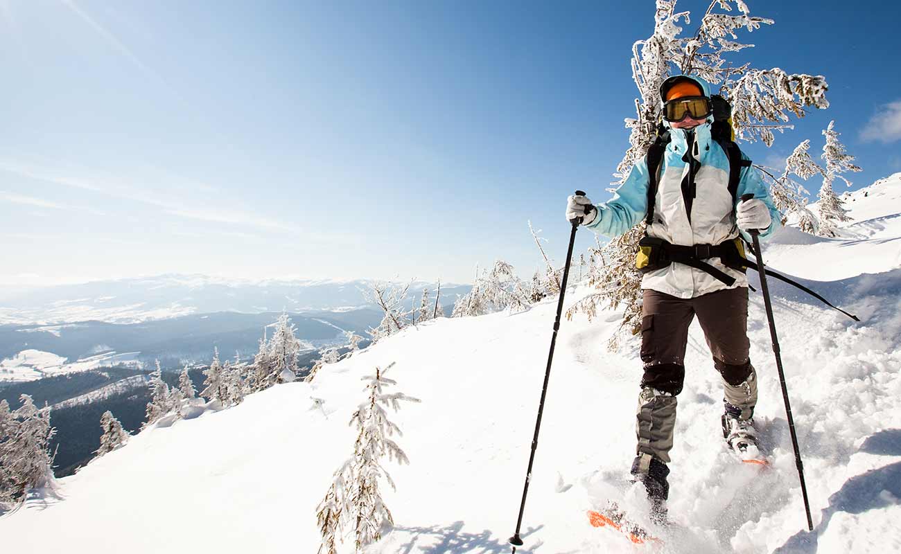Woman with snowshoes walking on a snowy path